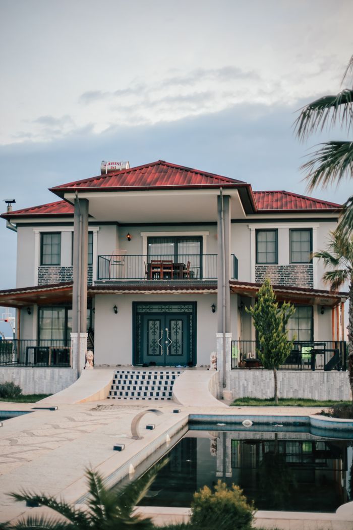 Luxurious villa with a swimming pool, palm trees, and balconies, captured in a serene residential area.