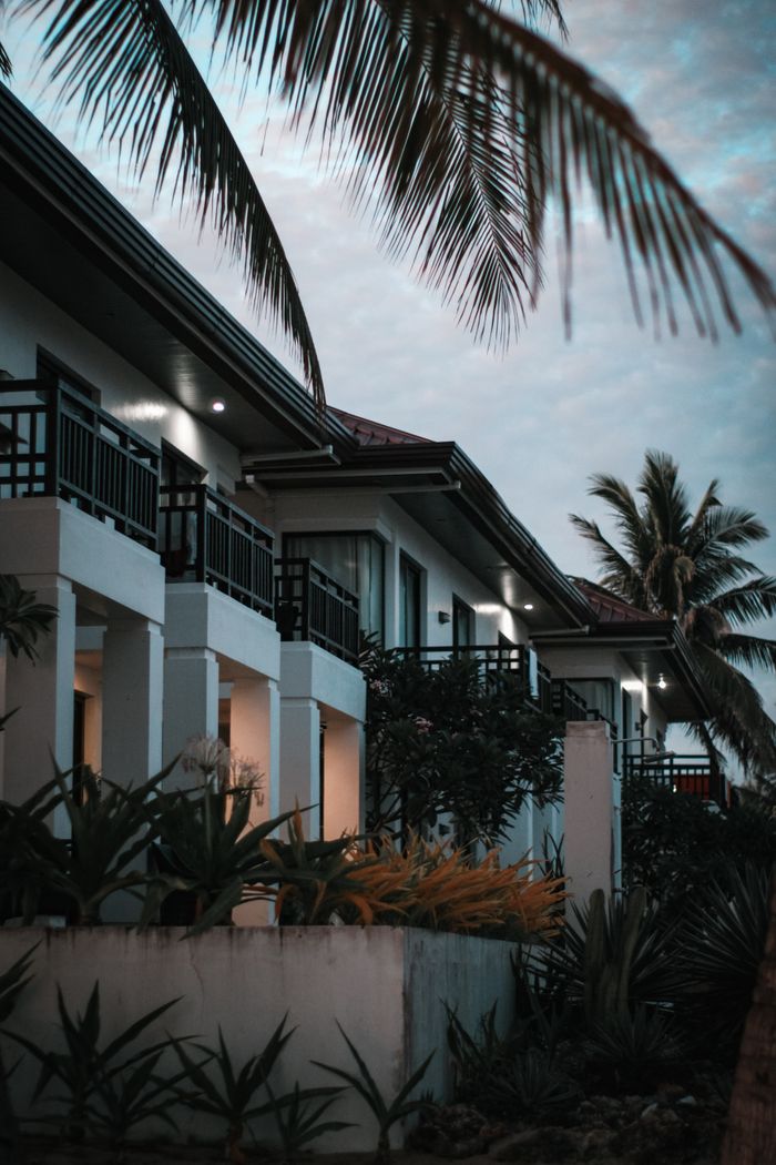 why-choose-us-01 Elegant resort building with palm trees at twilight, creating a tranquil tropical atmosphere.